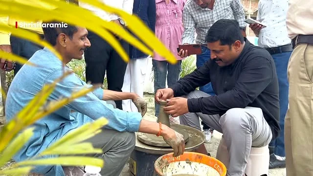 Two participants working with clay during an outdoor pottery demonstration as members of the school community watch