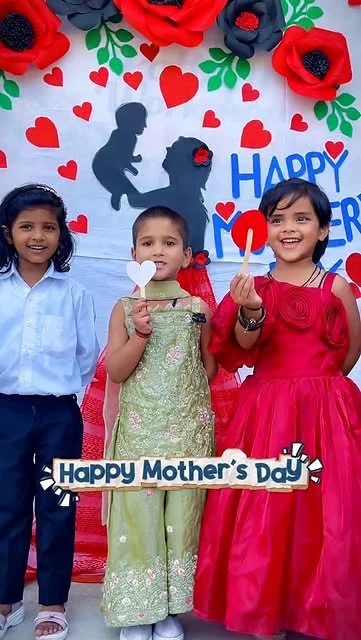 Young children smiling with handmade hearts during a Mother's Day school activity